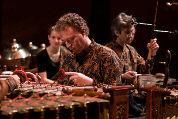 inmitten der bronzenen Kenongkessel sitzen Gamelanmusikser und der Geiger Martin Ehrhardt