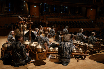 inmitten der bronzenen Kenongkessel sitzen Gamelanmusikser und der Geiger Martin Ehrhardt